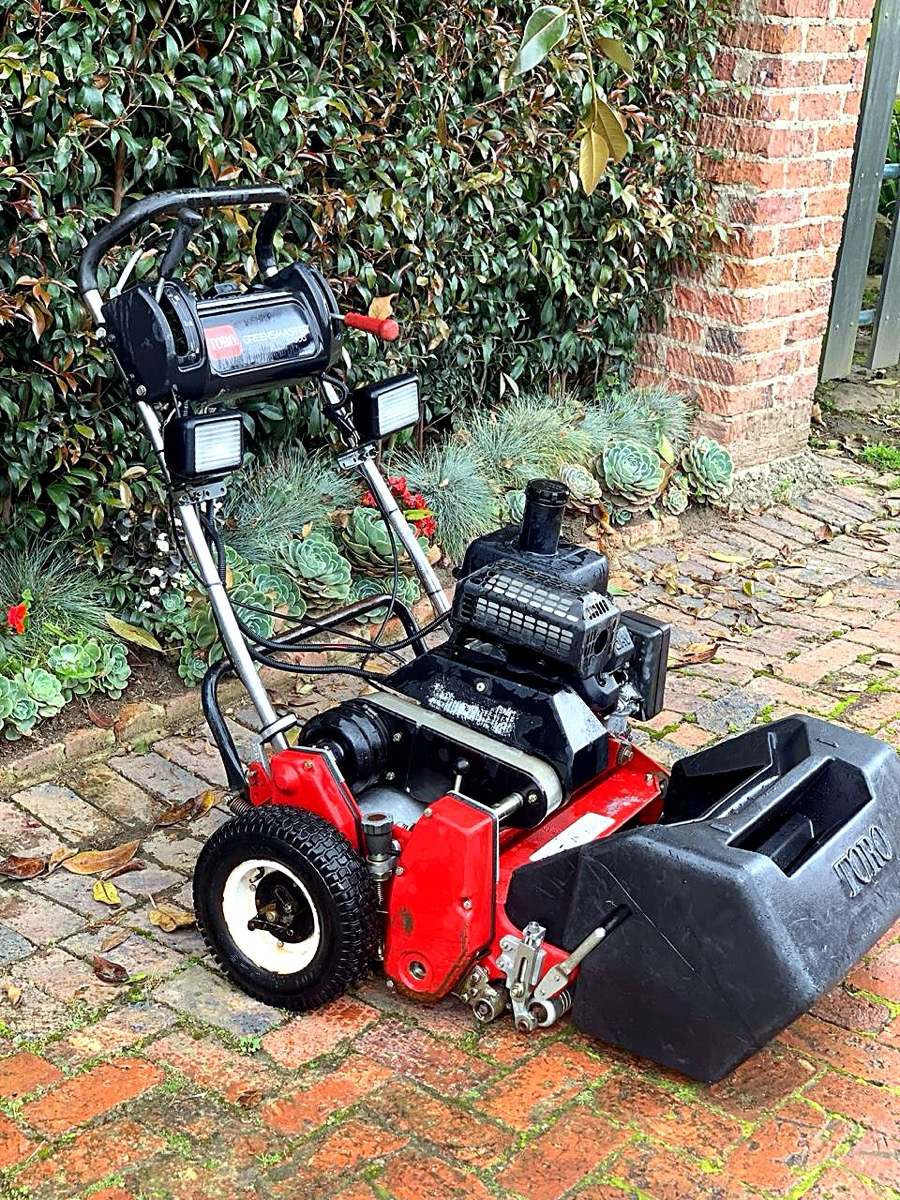 Cortadora de greens Toro Greensmaster con recogedor, en patio de adoquín